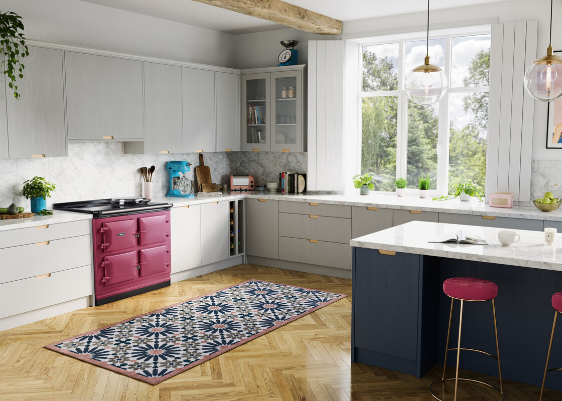 Helle, moderne Küche mit weißen Einbauschränken, einem pinken Herd, gemustertem Teppichläufer und großem Fenster mit Blick ins Grüne