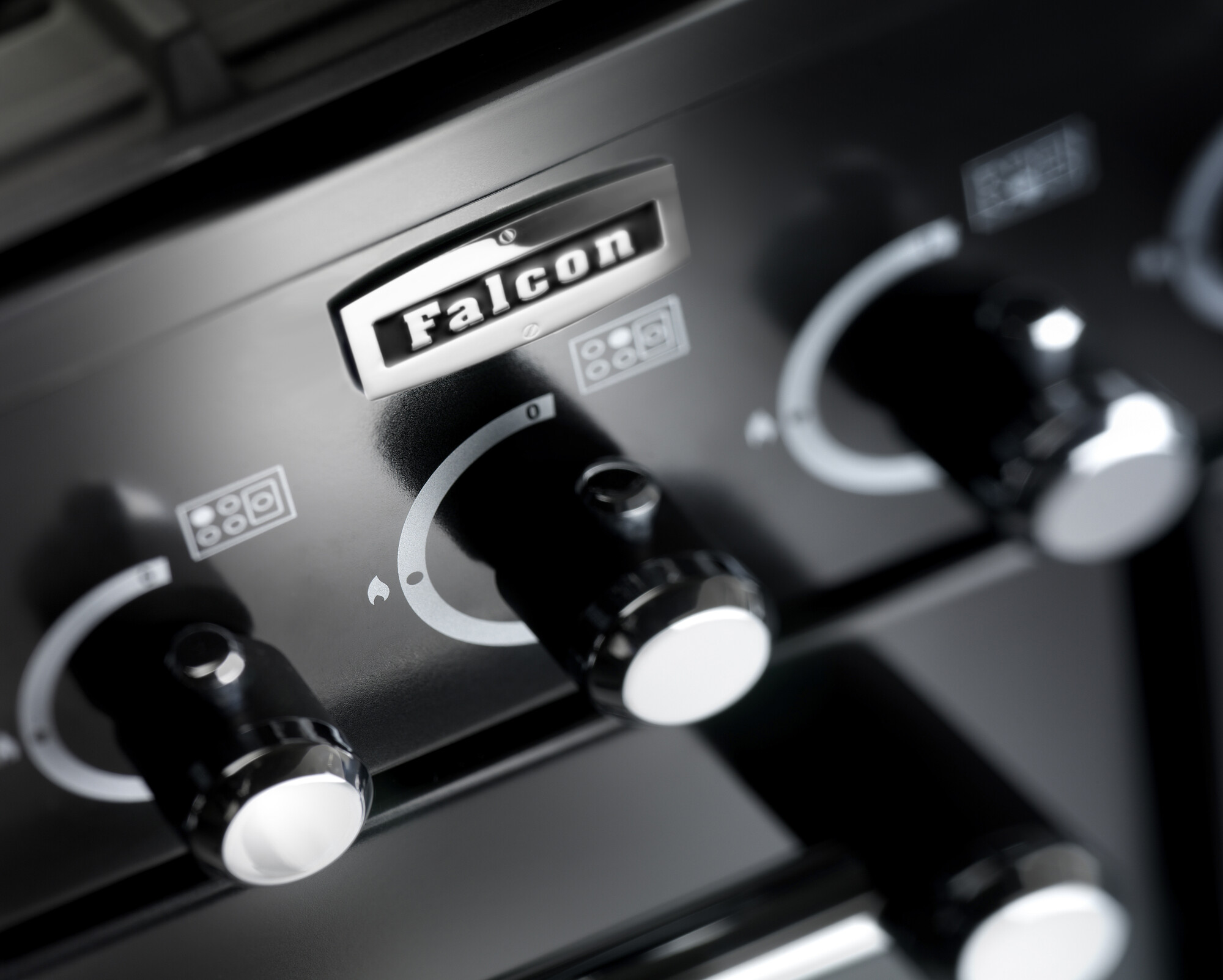 Nahaufnahme von Drehknöpfen und Logo eines Falcon Herdes, schwarz mit Bedienelementen
