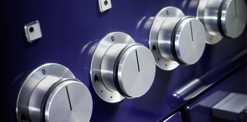 Nahaufnahme von mehreren Edelstahl-Drehknöpfen auf der Front eines modernen, blauen Herdes