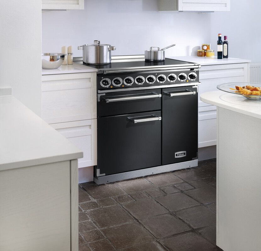 Moderner schwarzer Herd mit zwei Backofenfächern und mehreren Drehknöpfen, eingebaut in eine weiße Küche mit Kochutensilien auf der Arbeitsfläche