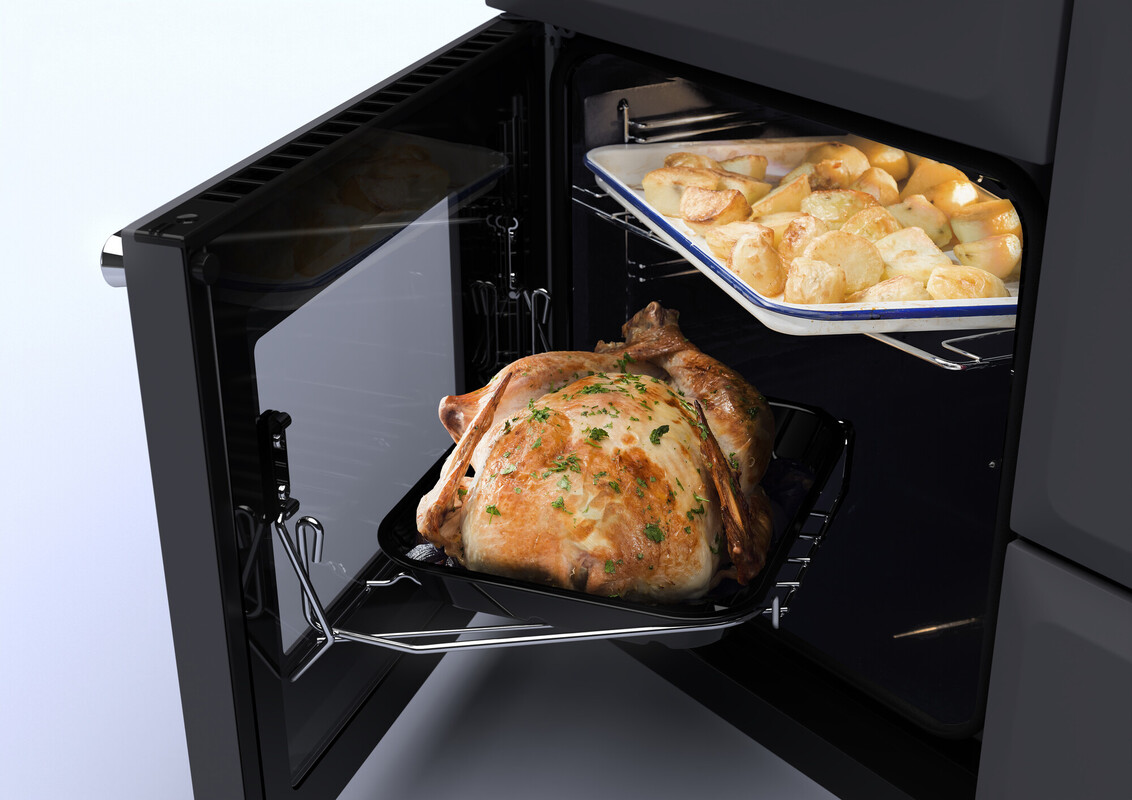 Ein frisch gebratenes Hähnchen auf einem Bräter und eine Auflaufform mit goldbraunen Kartoffeln befinden sich in einem geöffneten Backofen.