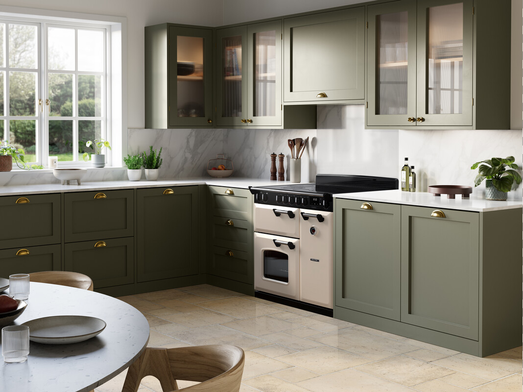 U-Form-Landhausküche in Salbeigrün mit Shaker-Kassettenfronten, goldenen Griffmuscheln, weißer Quarz-Arbeitsplatte, Rückwand in Marmor-Optik und cremefarbenem Range Cooker