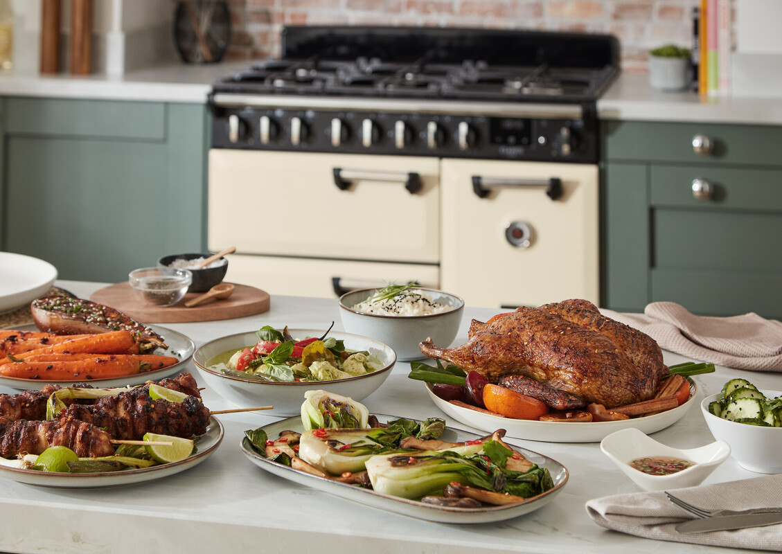 Cremefarbener Range Cooker/Standherd mit großem Backofen und Mehrzonen-Kochfeld in moderner Küche; servierte Speisen zeigen die hohe Kapazität und gleichmäßige Garleistung des Herds