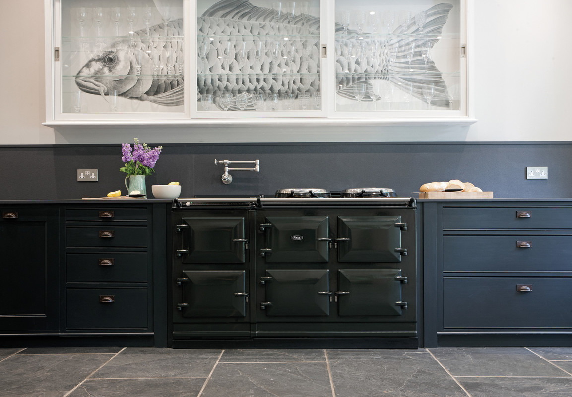 Elegante schwarze Küche mit großem Herd, lila Blumen, Broten und einzigartigem Schrank mit Fischmotiv hinter Glas