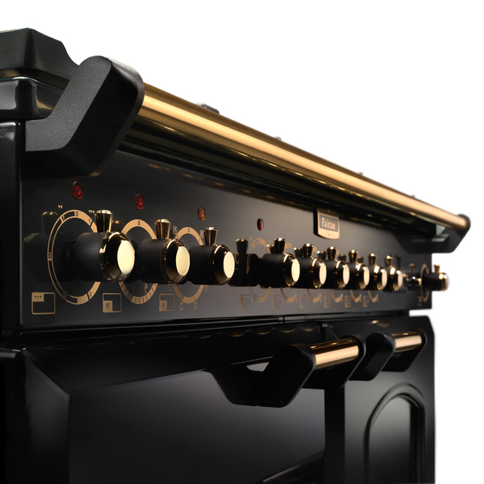 Nahaufnahme eines luxuriösen Herds in Schwarz mit goldenen Details und mehreren Drehknöpfen