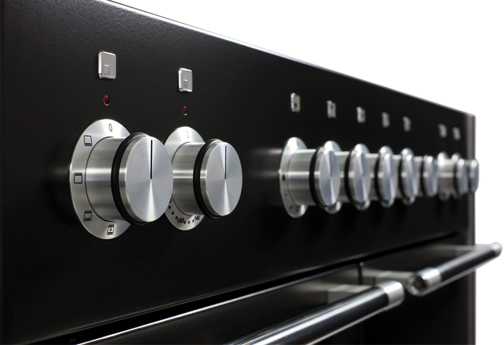 Detailansicht eines modernen Herdes mit mehreren Edelstahl-Drehknöpfen zur Steuerung von Herdplatten und Ofen