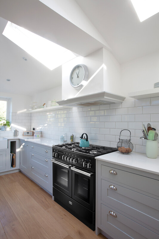 Helle Küche mit Gasherd, grauen Schränken und weißer Fliesen