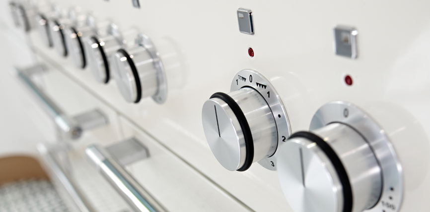 Nahaufnahme von silbernen Drehknöpfen an einem modernen Herd zur Einstellung von Temperatur und Funktionen