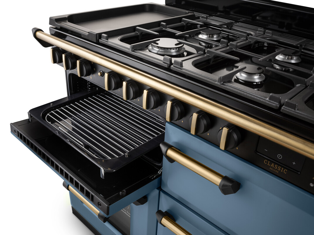 Detailansicht: großer Range Cooker/Gasherd mit Guss-Kochfeld, Wokbrenner, Griddle/Plancha, offenem Grillfach und Backofen; blaues Design mit goldenen Bedienelementen – ideal für vielseitiges Kochen und Backen